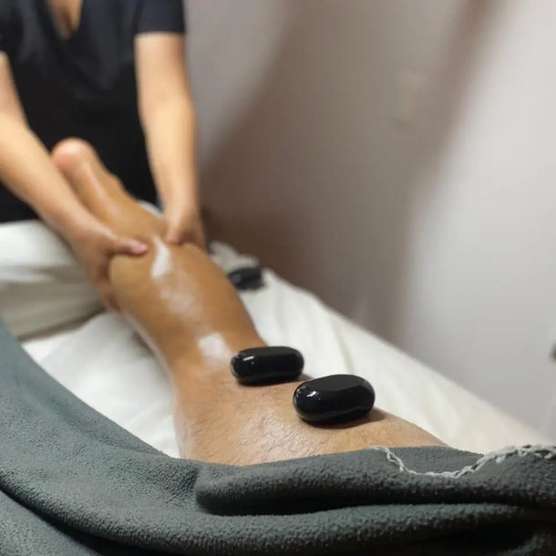 Masaje con piedras calientes en las piernas para relajación y bienestar