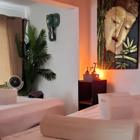 Sala doble de spa con dos camillas, iluminación cálida y decoración tropical